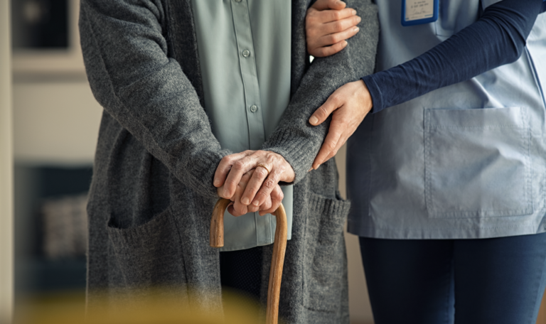Nurse helping elderly patient walk safely at home during a nurse home visit